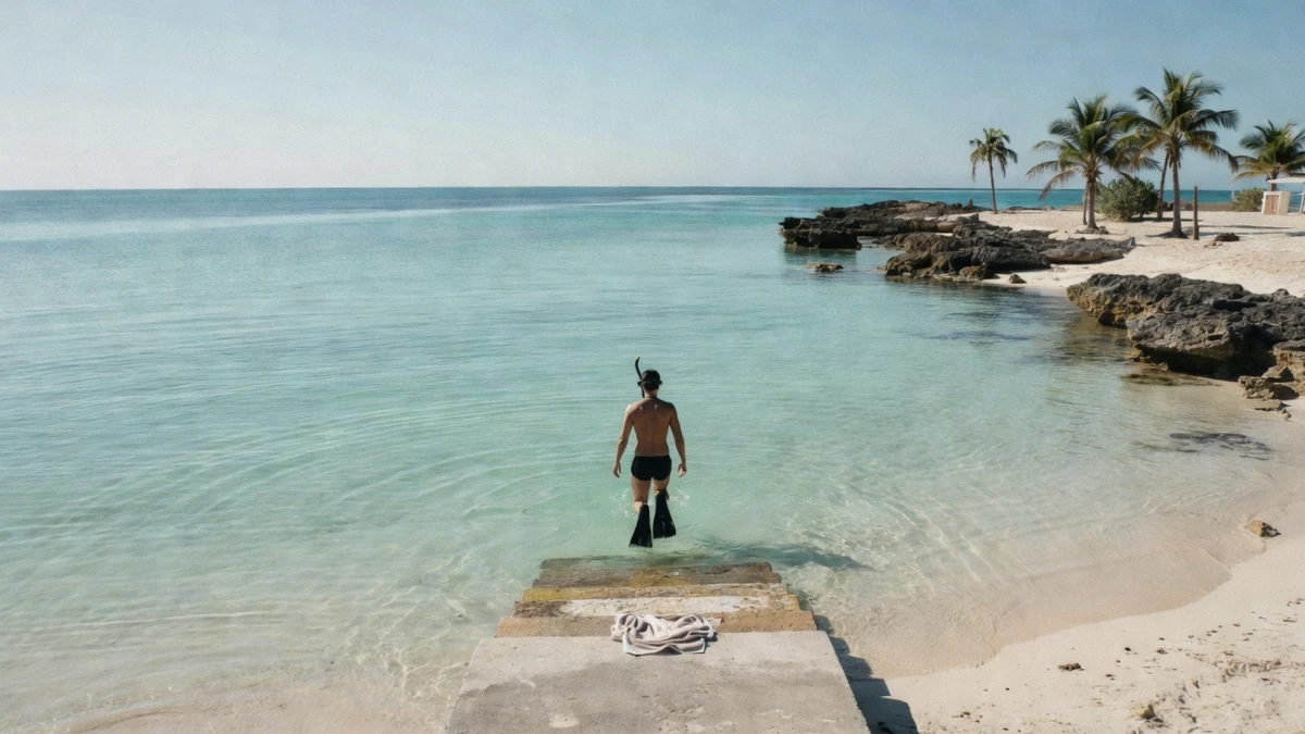 A snorkeler walking down steps into calm, clear water at a Cozumel shore snorkeling beach club on the island's leeward coast