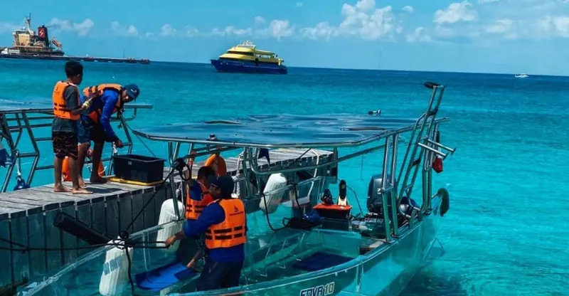A transparent glass boat floating over coral and fish on a Cozumel snorkeling tour on the calm north side of the island